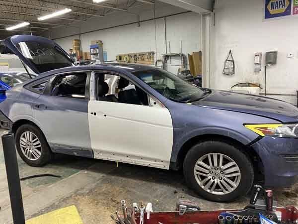 A blue and white car is being painted in a garage.