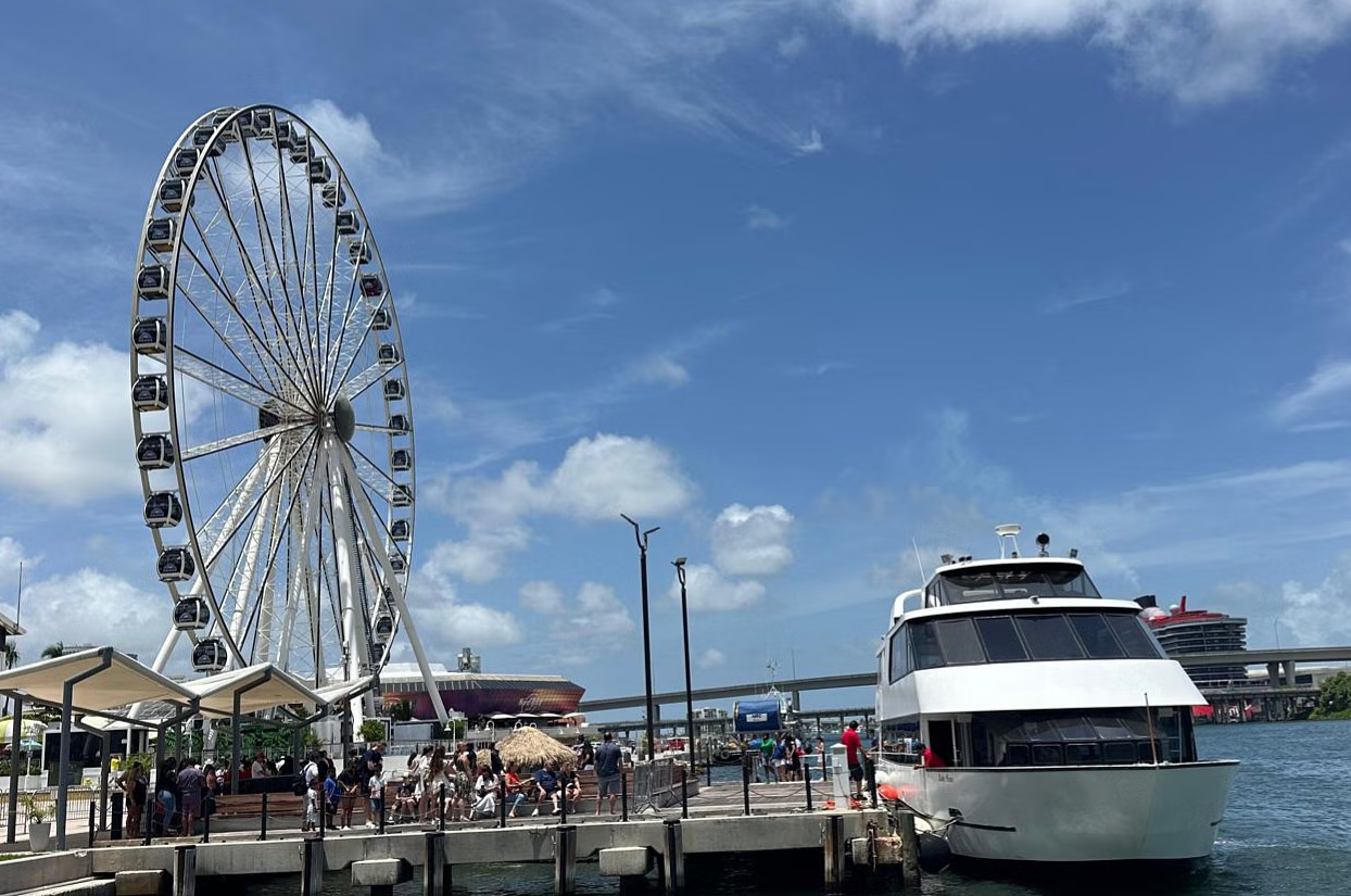 Ferris wheel and boat docked at a pier on a sunny day with blue sky.
