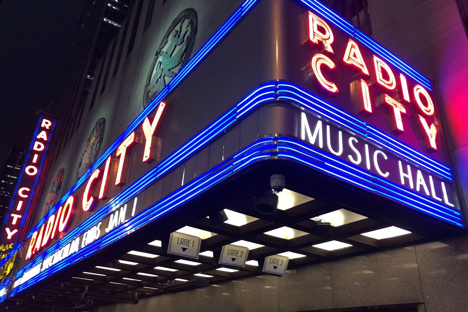 Radio City Music Hall marquee with neon lights against a dark sky. 