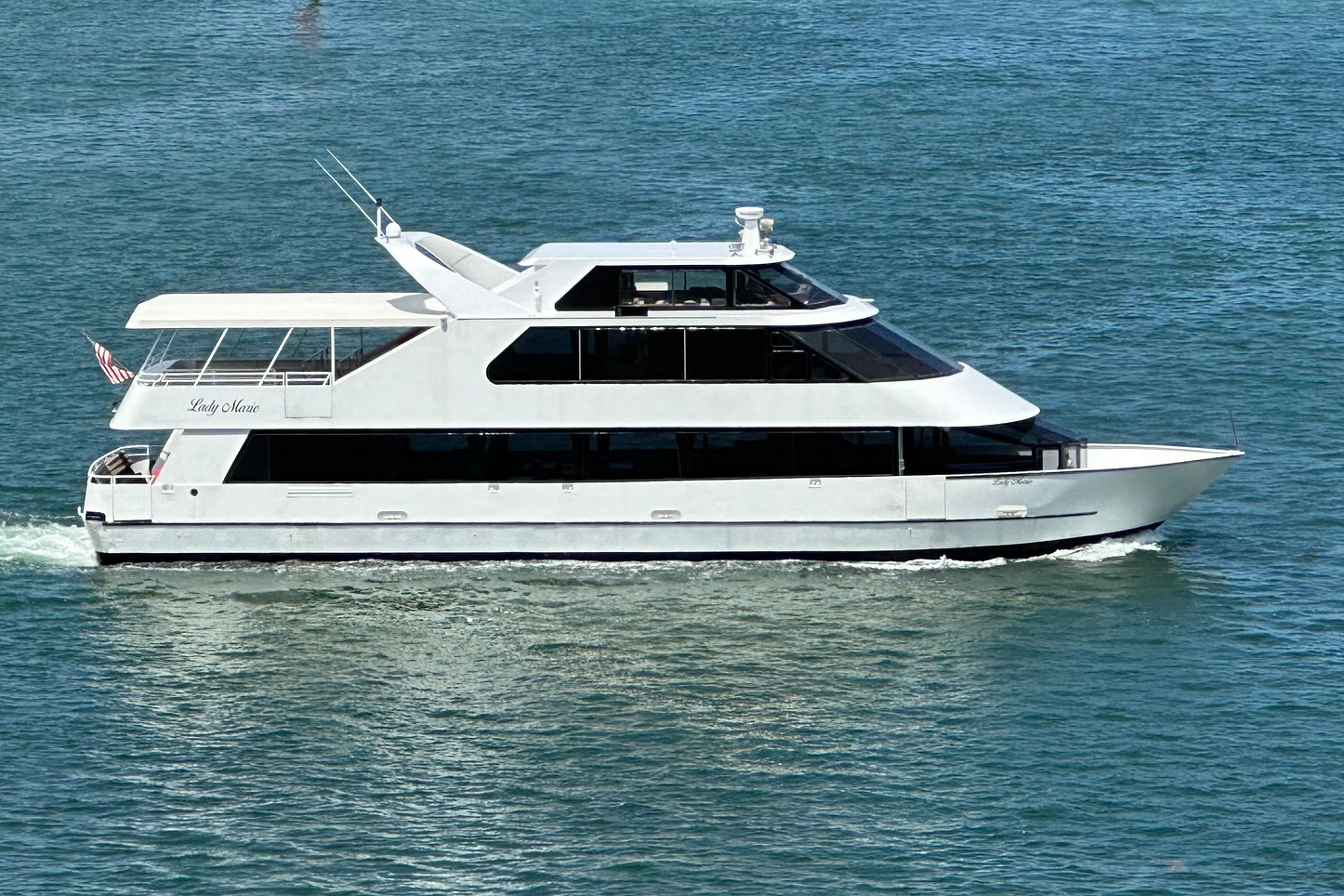 White yacht on blue water with windows and a top deck.