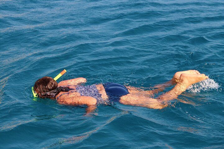 Girl snorkeling in blue ocean water.