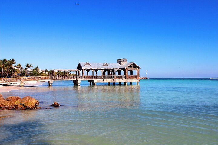Wooden pier building over turquoise water, under a bright blue sky.