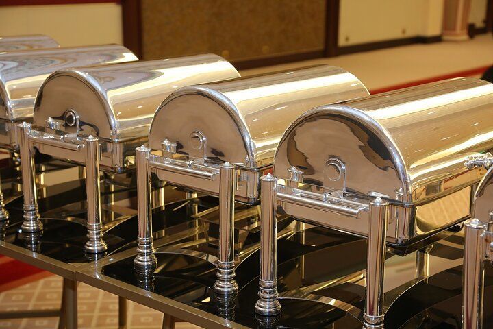 Stainless steel chafing dishes lined up on a buffet table, ready for food service.