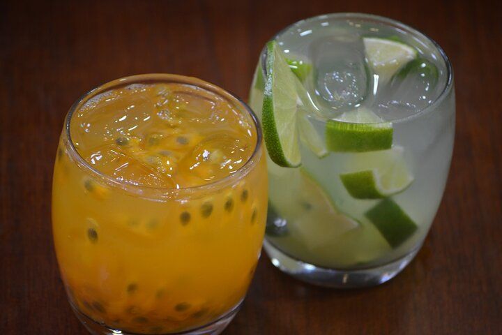 Two cocktails: one orange passionfruit, the other with lime wedges, both in clear glasses.