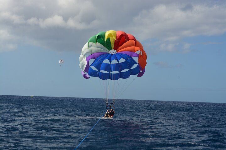 Colorful parasail over blue ocean, person enjoying the ride.