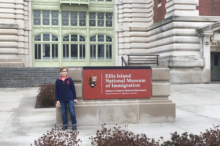 Person standing in front of Ellis Island National Museum of Immigration sign.