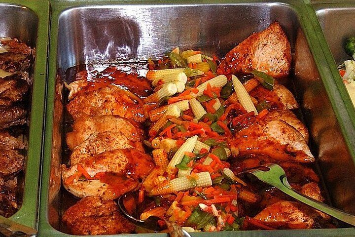 Chicken pieces with mixed vegetables and sauce in a serving tray.