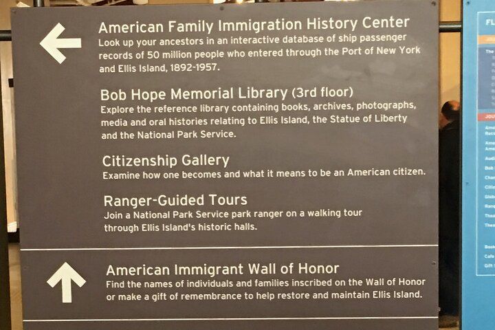 Sign with arrows pointing to destinations: Immigration History Center, library, gallery, tours, and Wall of Honor.