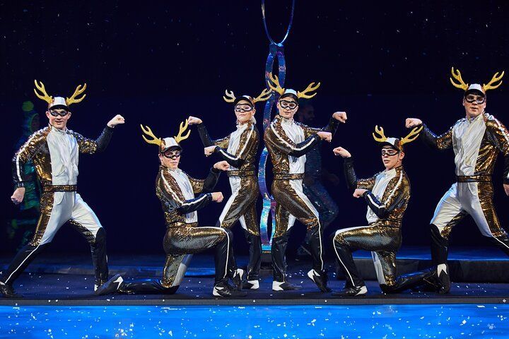 Six performers in reindeer costumes pose on stage.
