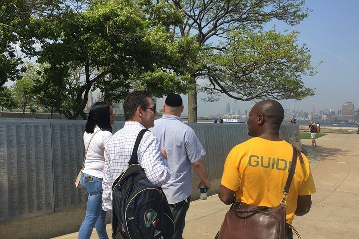 Group of people walking near a gray wall with a 