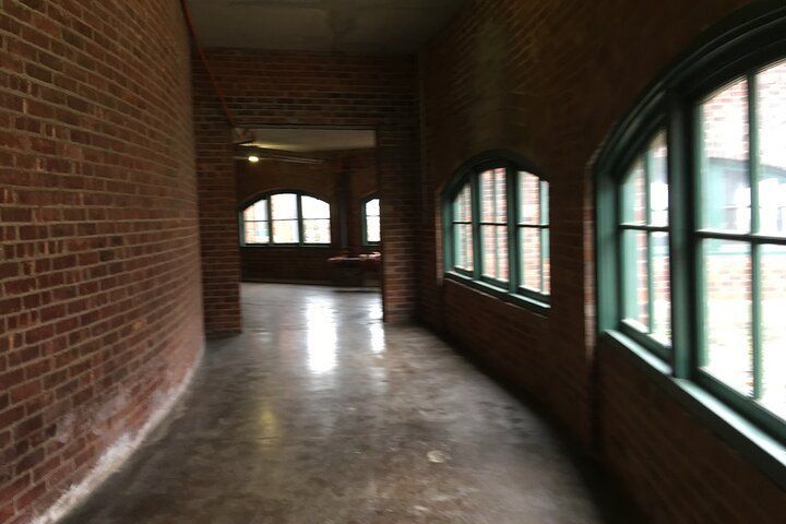 Brick hallway with curved wall and arched windows with green frames.