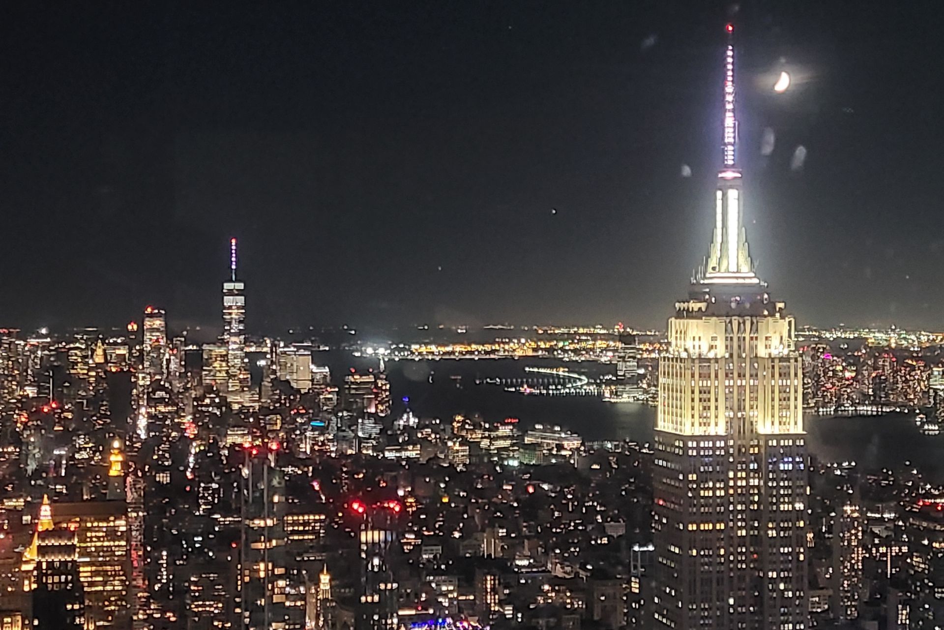 Night view of New York City skyline with the brightly lit Empire State Building in the foreground.