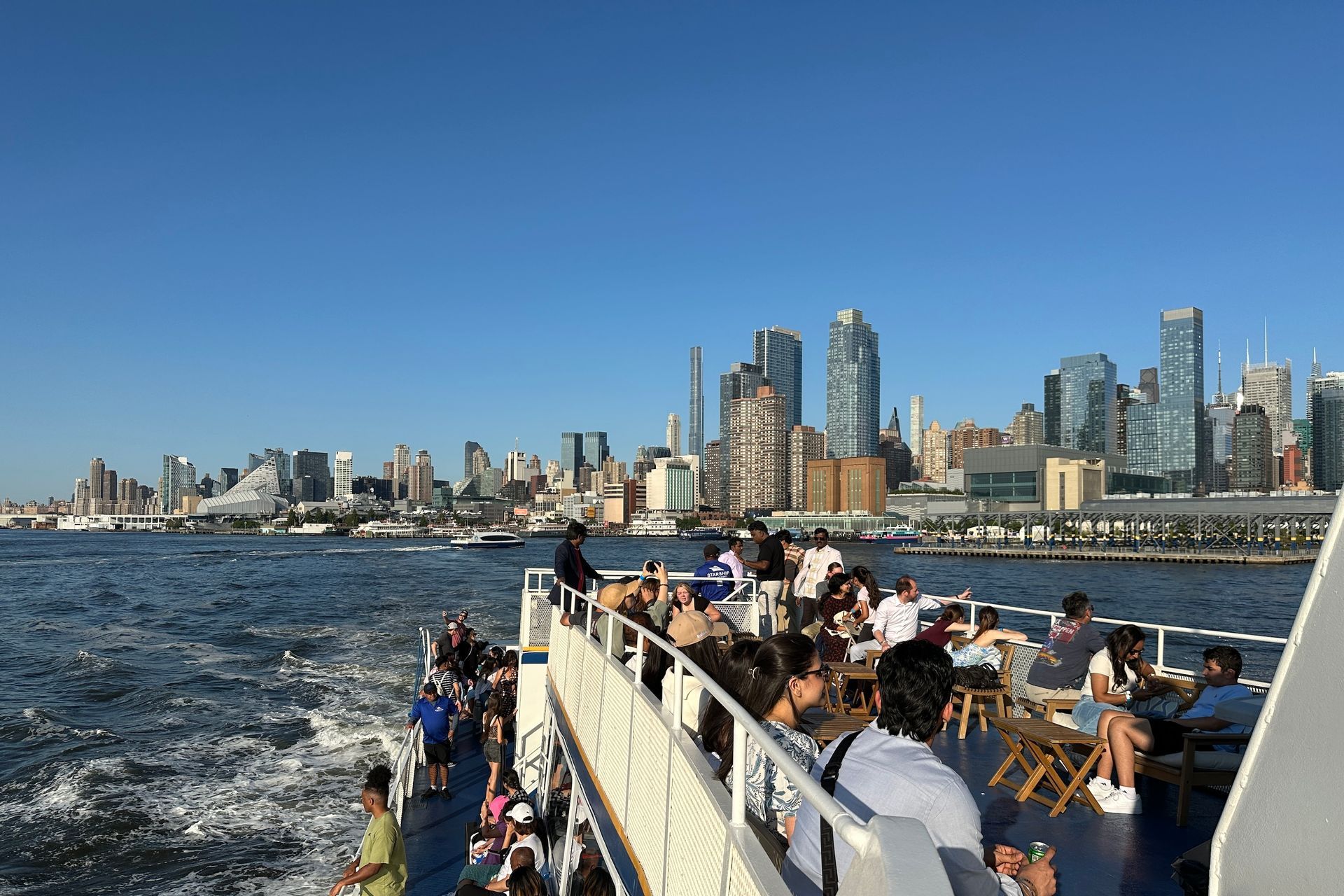 People on a boat viewing a cityscape on a sunny day.
