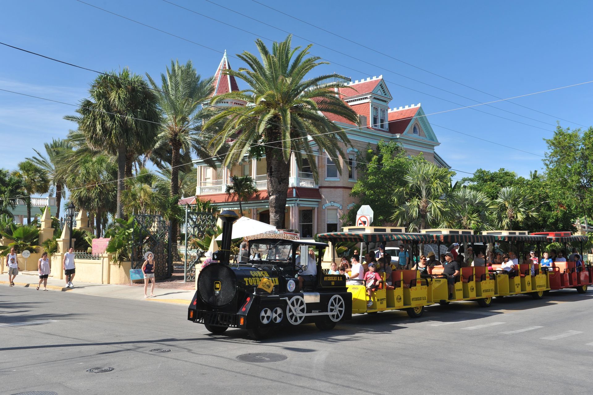 Train carrying tourists passes a colorful Victorian house in Key West, Florida.
