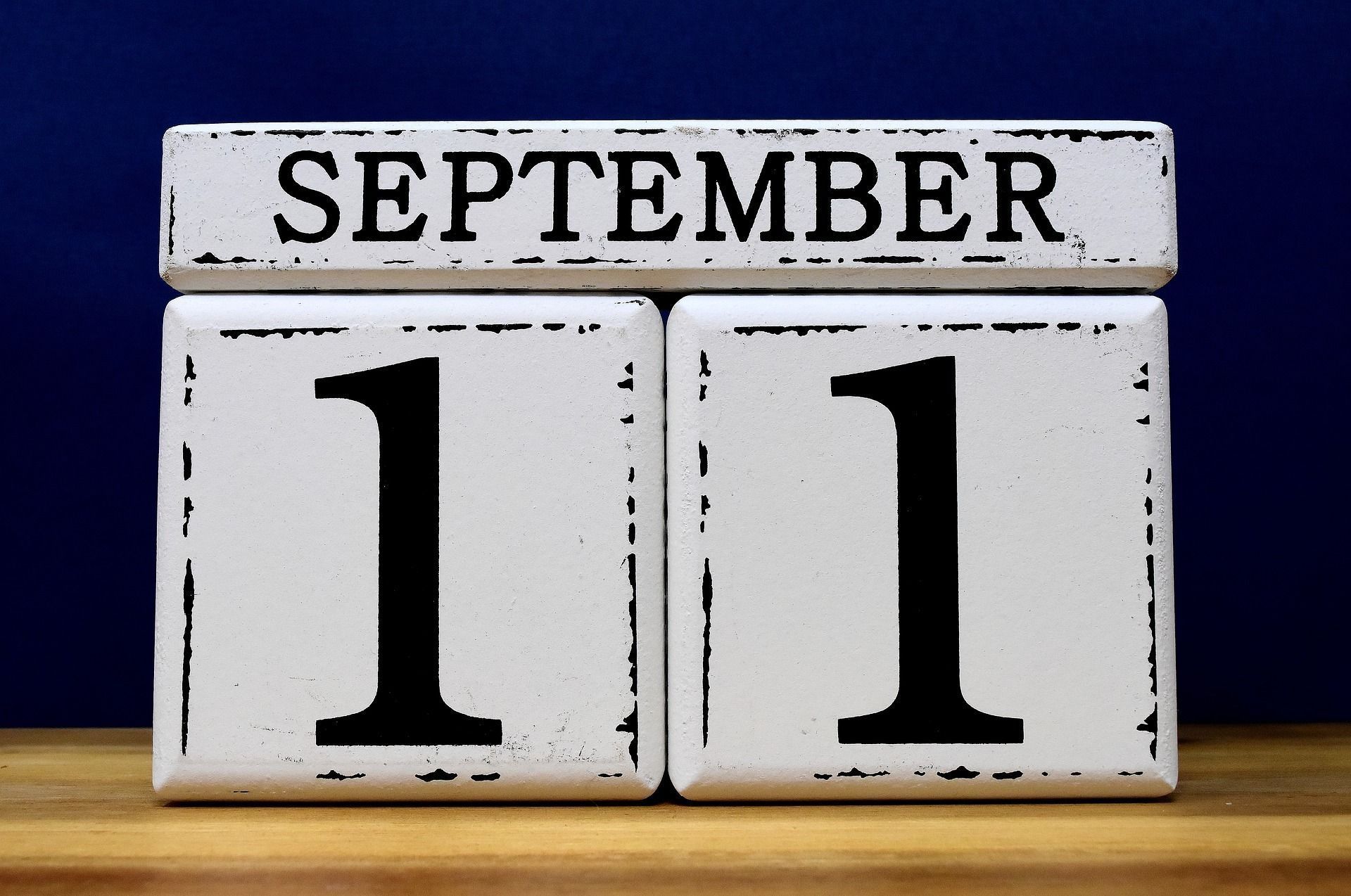 Wooden calendar showing September 11 against a dark blue background and wooden surface.