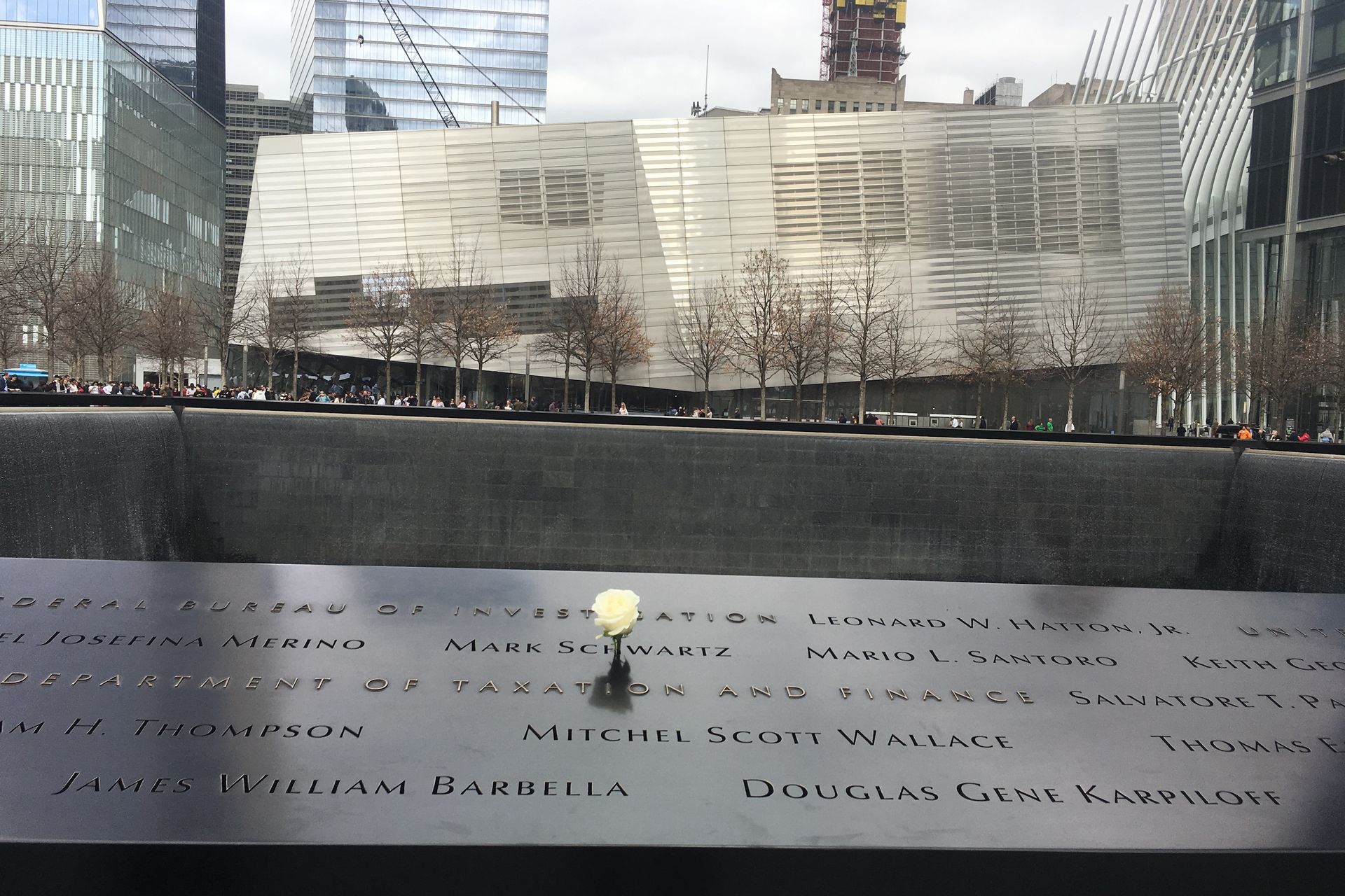 9/11 Memorial with water cascading into a black pool, names etched in the surface, and a single white rose.