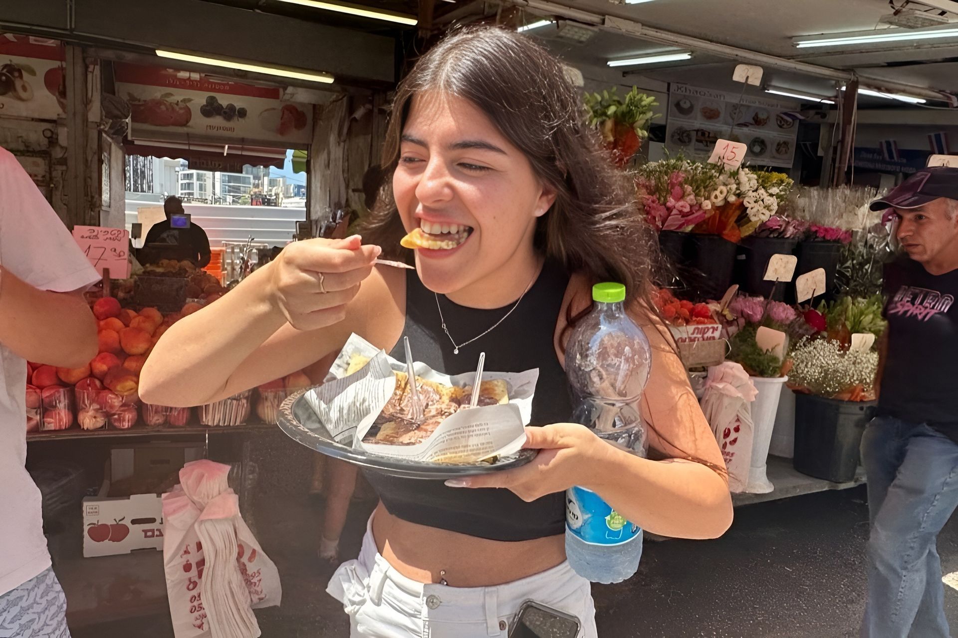 A girl enjoying a plate of food at a street market.