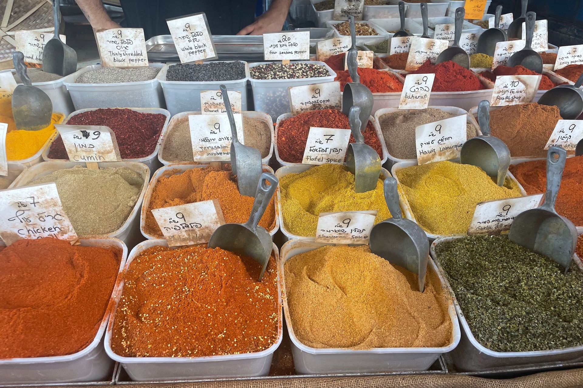 Spices for sale in market bins; bright orange, red, and yellow hues.