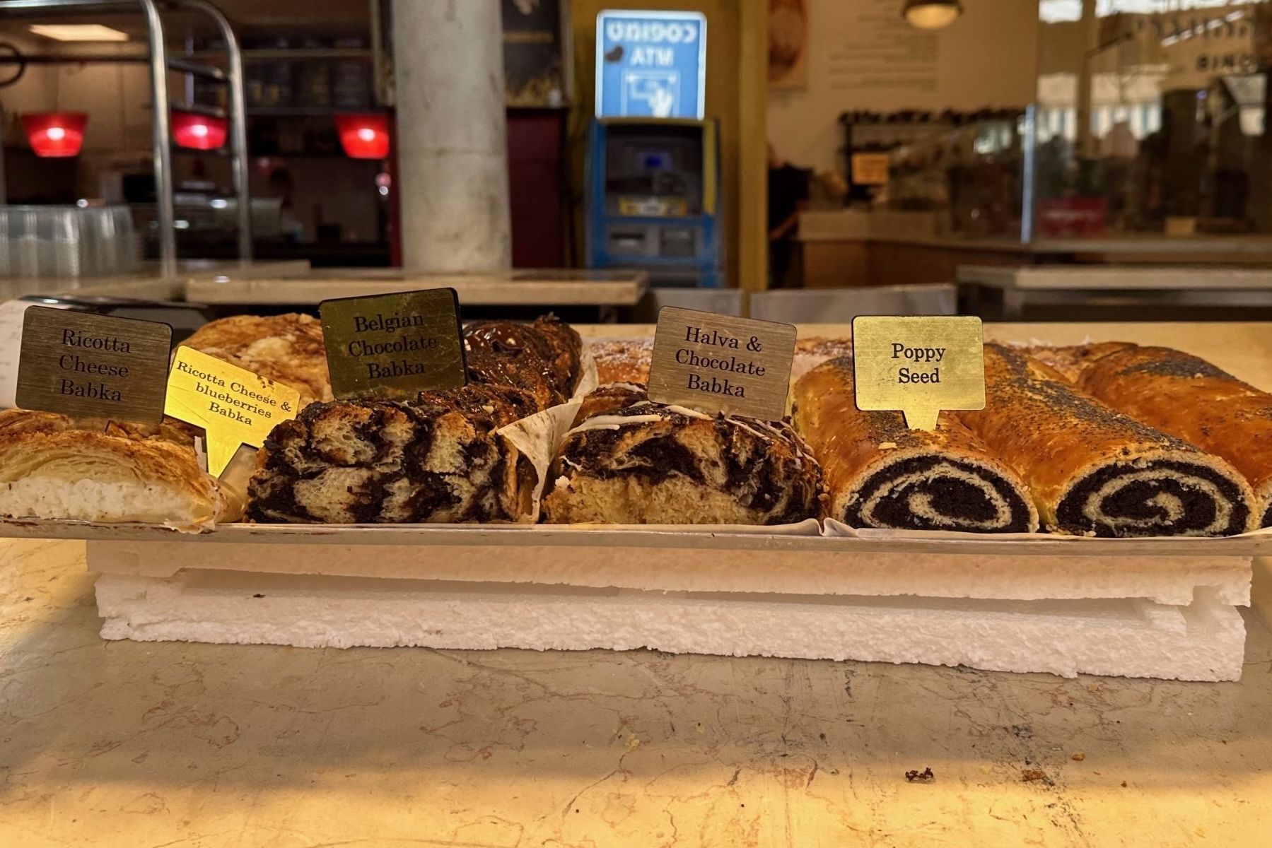 Assortment of baked goods, including poppy seed rolls, displayed on a counter in a cafe setting.
