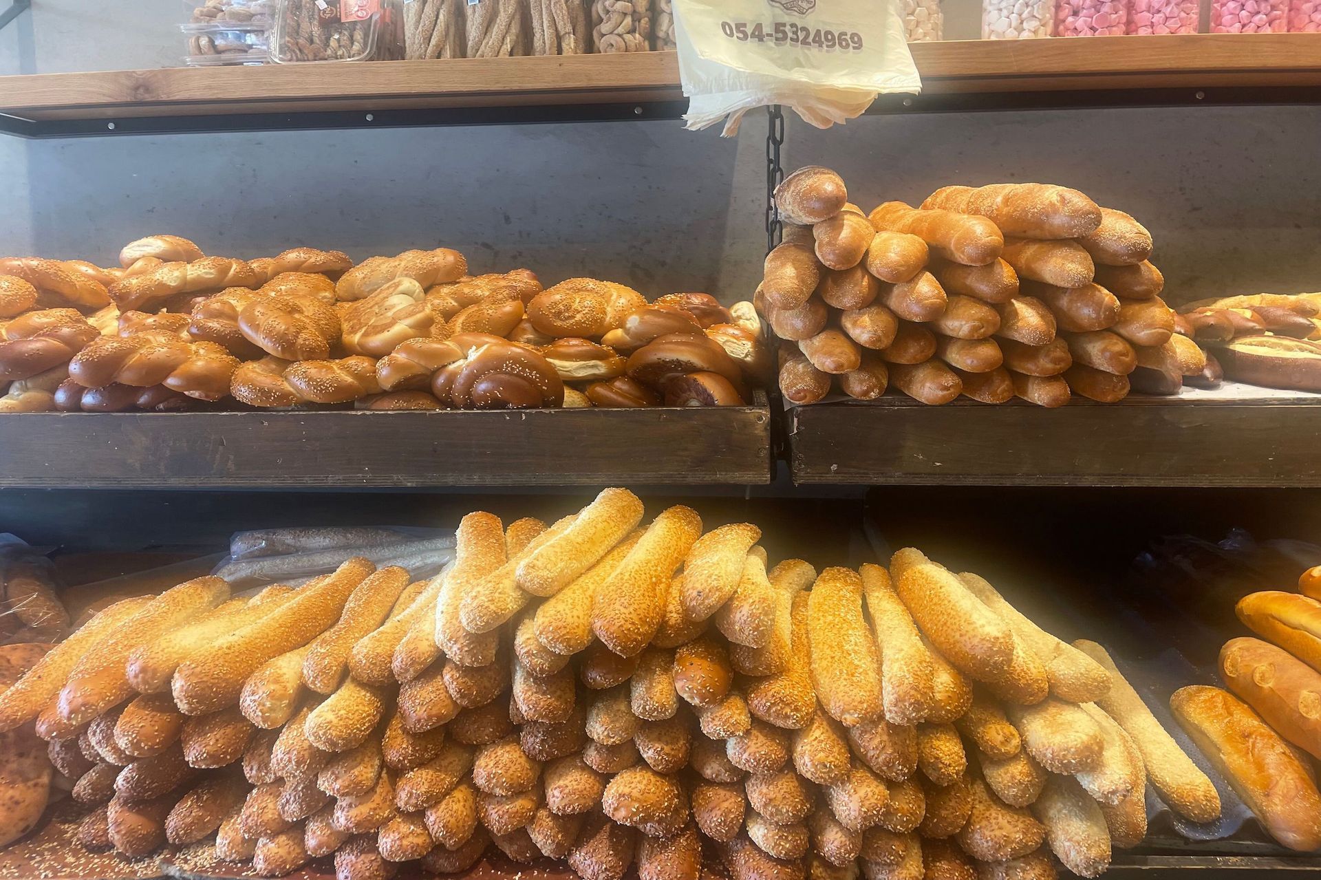 Bakery display of assorted baked goods, including twisted pastries and sesame-covered bread sticks.