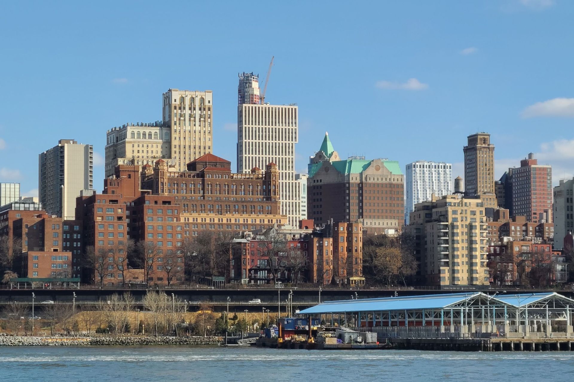 Skyline of Brooklyn, NY, with skyscrapers of varying heights and styles against a clear blue sky.