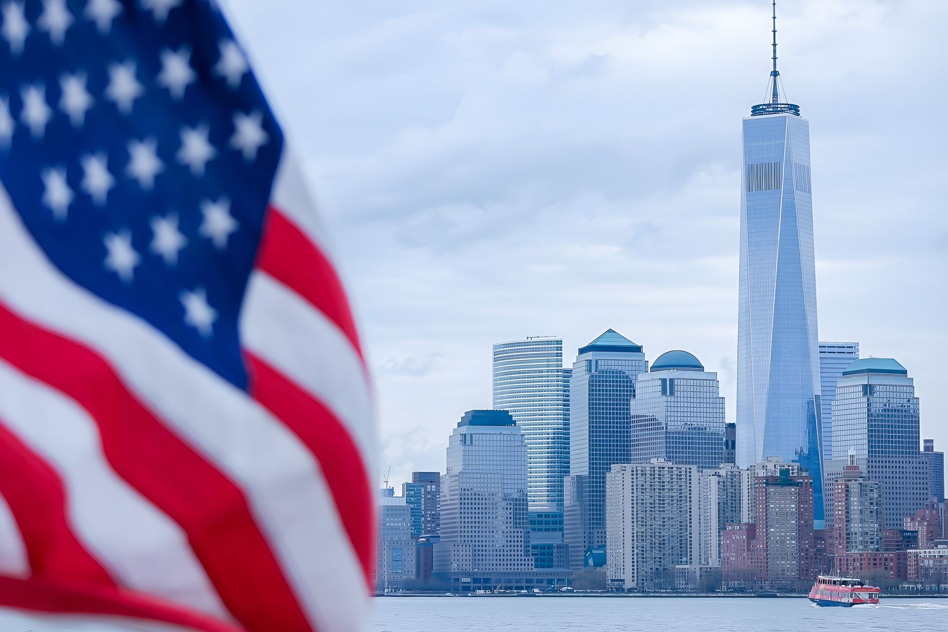 American flag in the foreground, New York City skyline with One World Trade Center in the background.