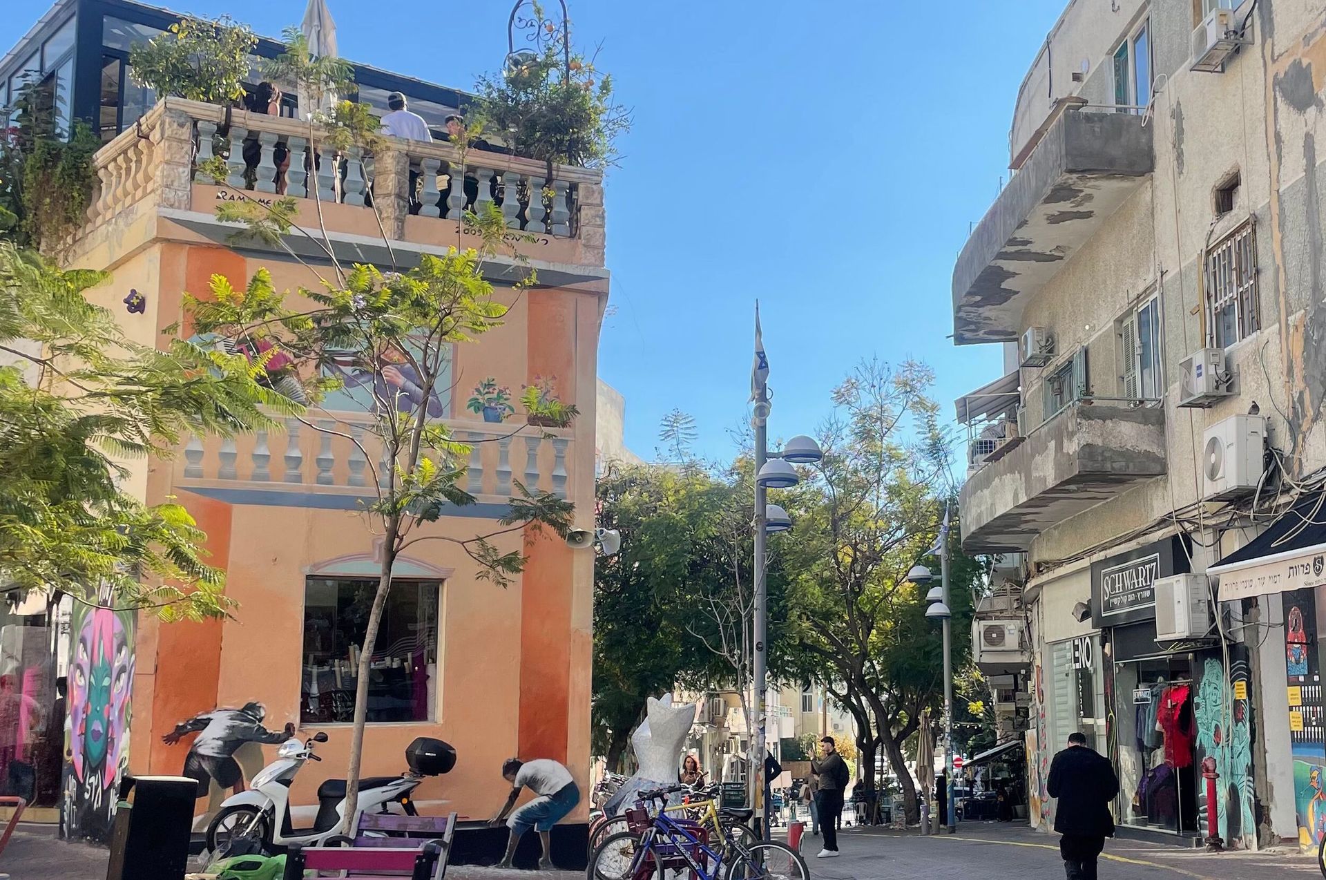 Street scene with orange building, graffiti, and people in Tel Aviv.