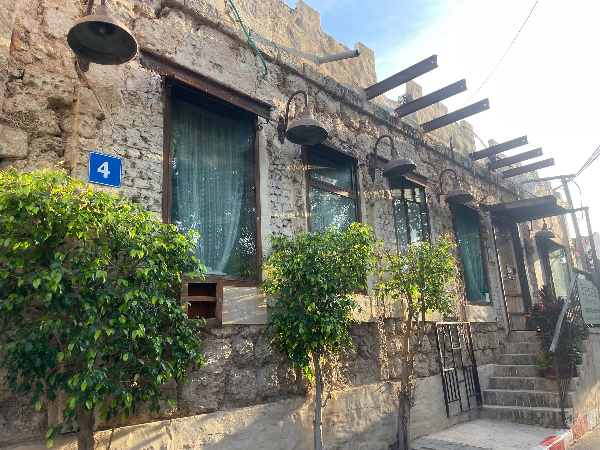 Old stone building with green plants, windows, and number 4 sign.