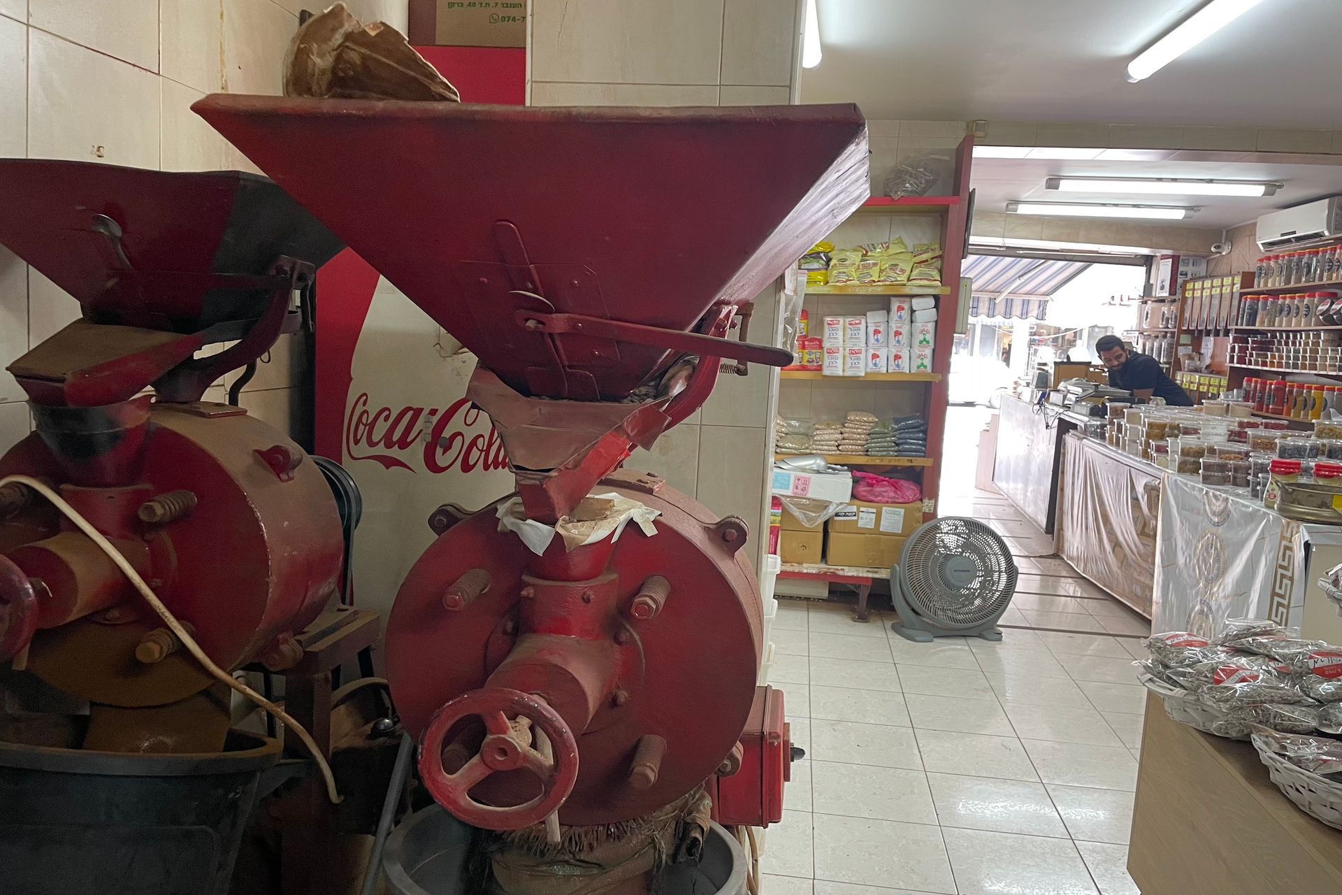 Red coffee grinders in a store, person shopping in the background.