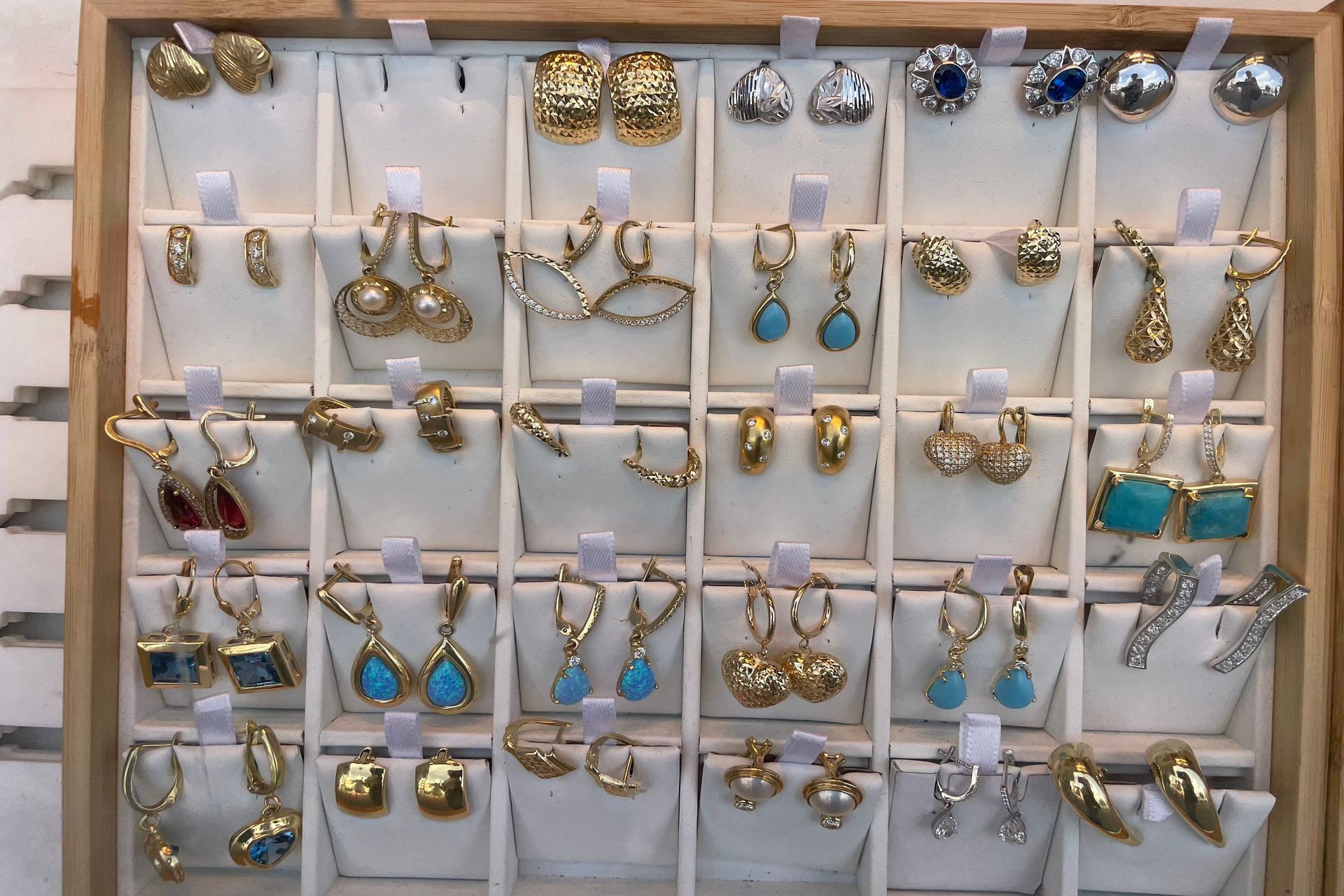 Earring display case with gold and silver earrings, some with turquoise and gems.