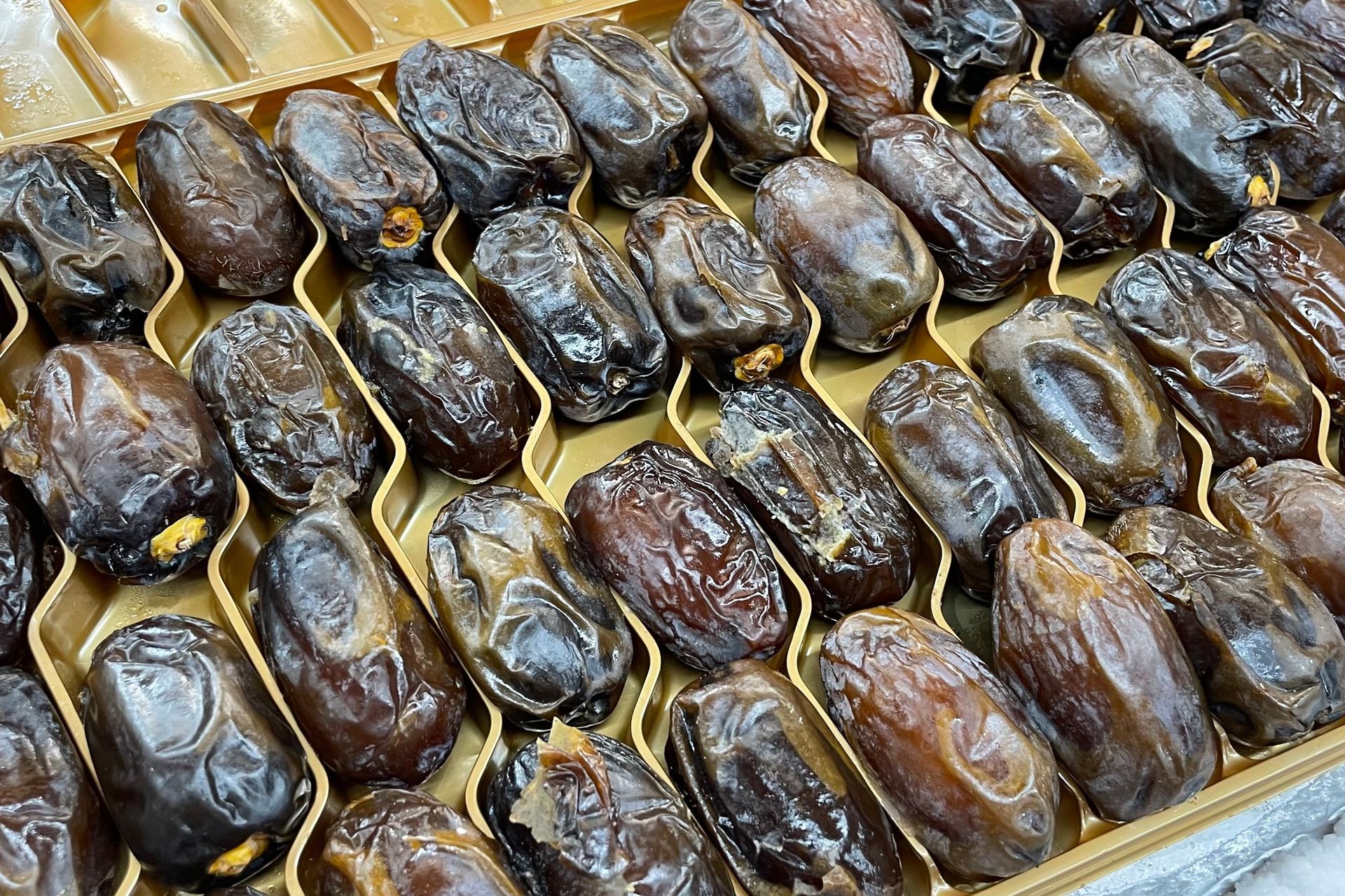 Box of dark brown dates in a gold-colored tray.