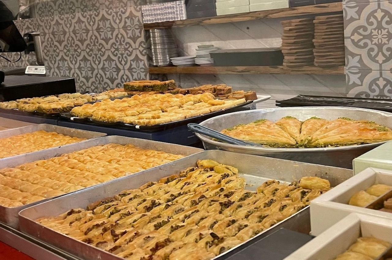 Trays of assorted baklava pastries at a bakery, close-up.