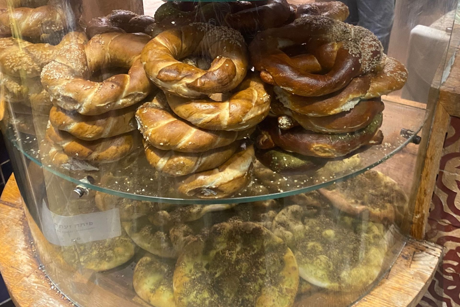Pretzels and flatbreads displayed in a bakery case.