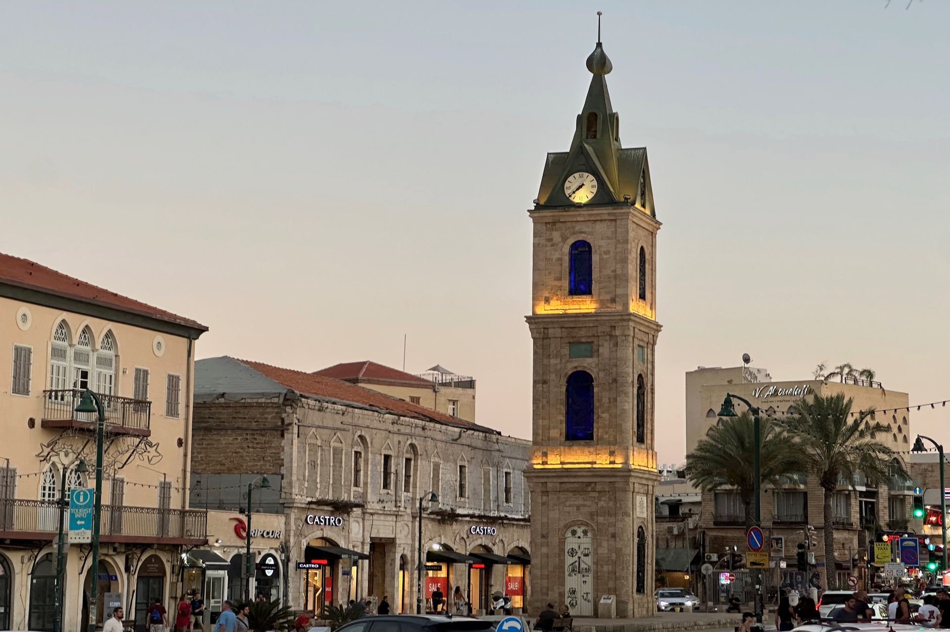 Clock tower in Jaffa, Israel, surrounded by buildings and people; dusk lighting.