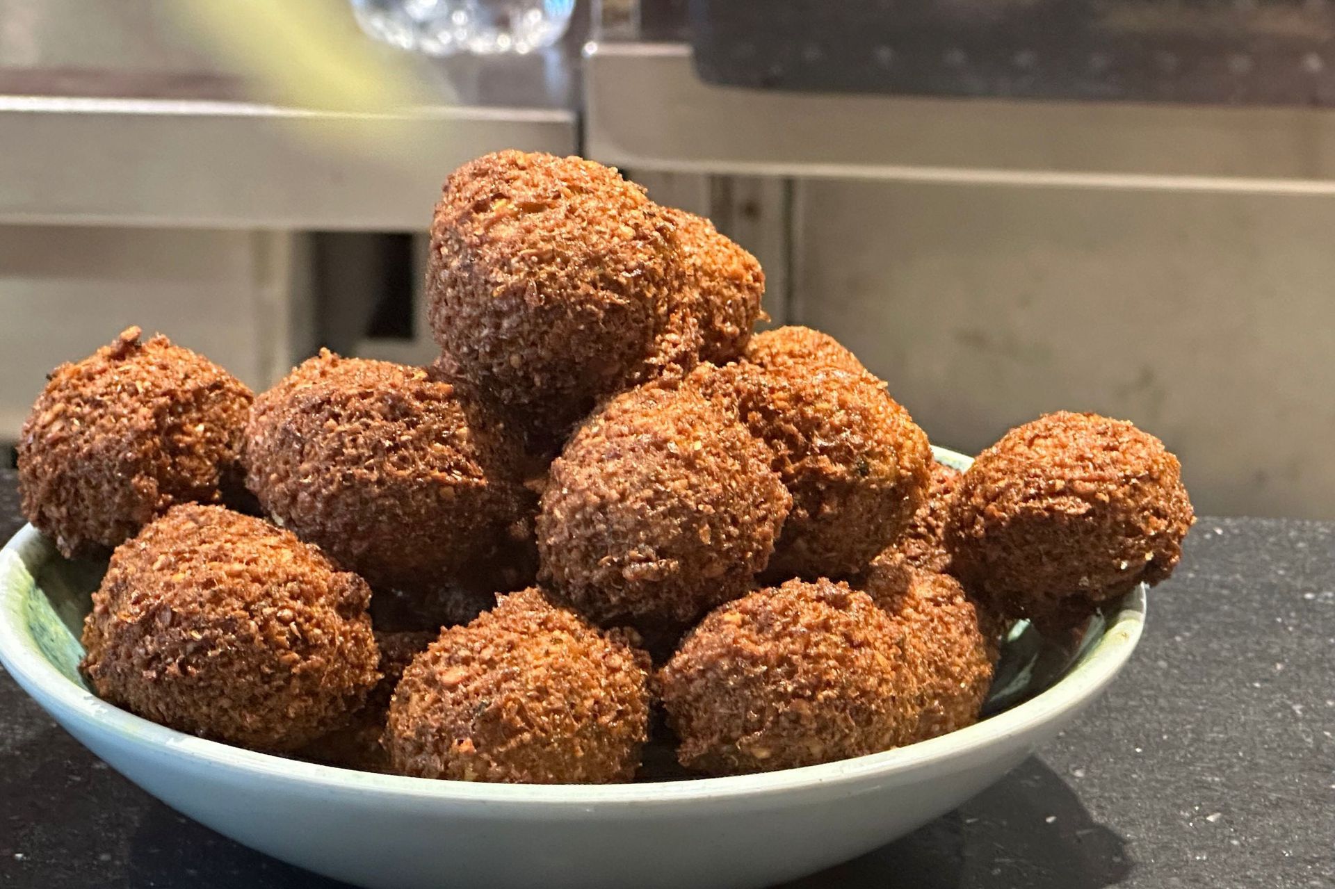 Brown chocolate truffles in a light blue bowl on a dark surface.