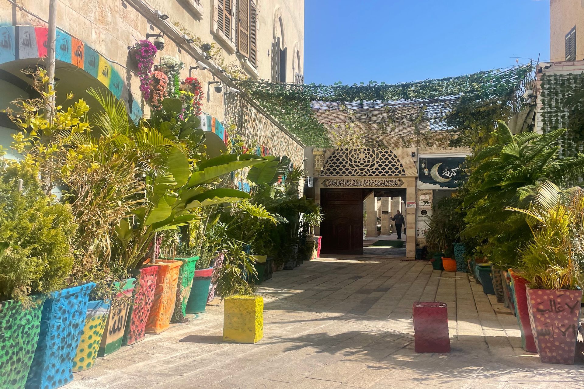 Entranceway with colorful planters, lush greenery, and ornate architectural details.