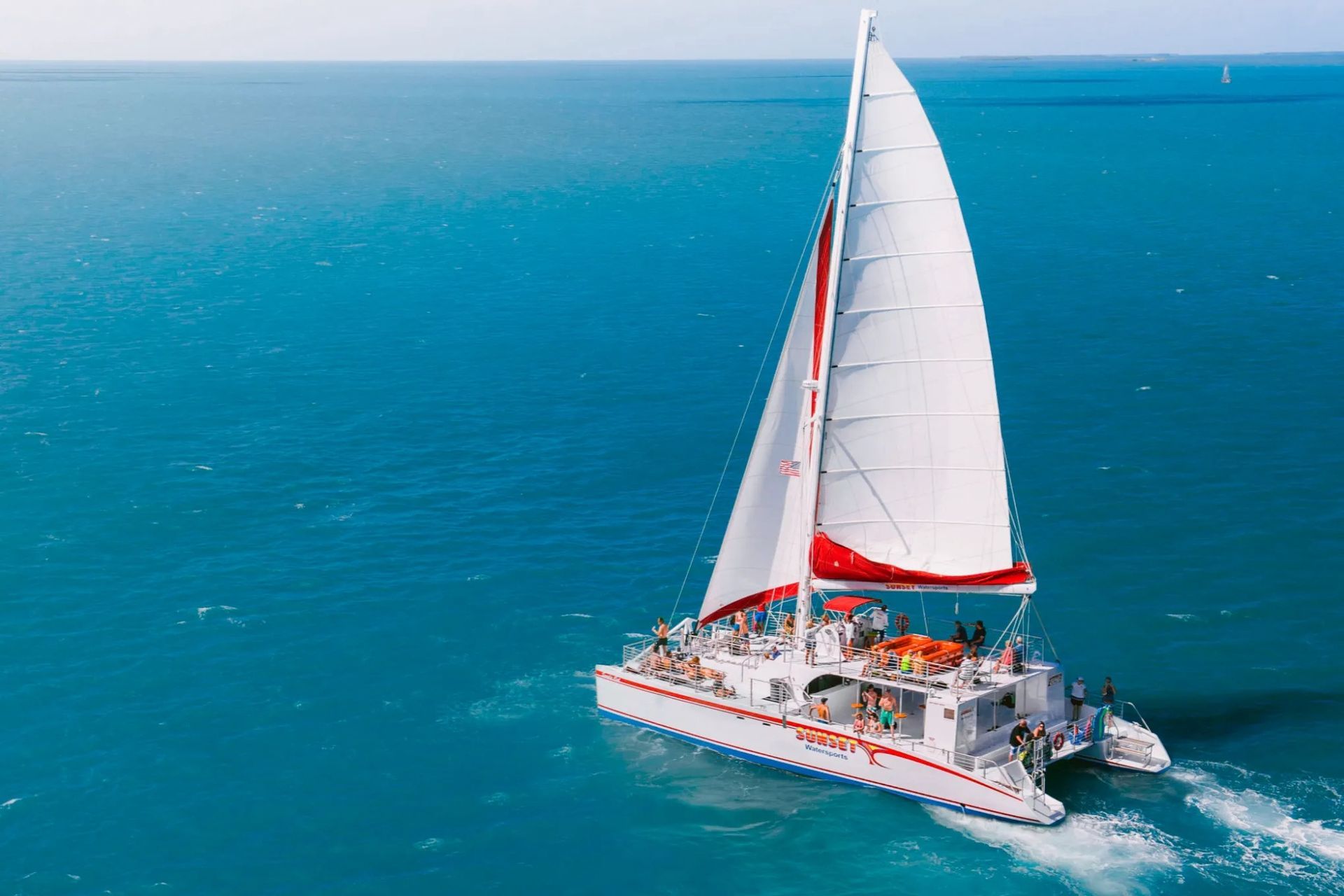 Sailboat on blue water with passengers; sunny day.