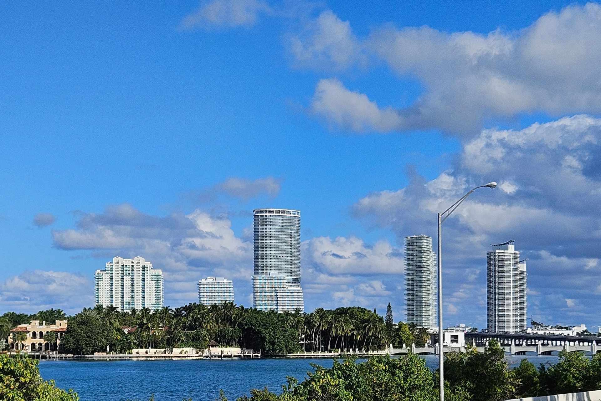 Buildings by a body of water under a blue sky with clouds.