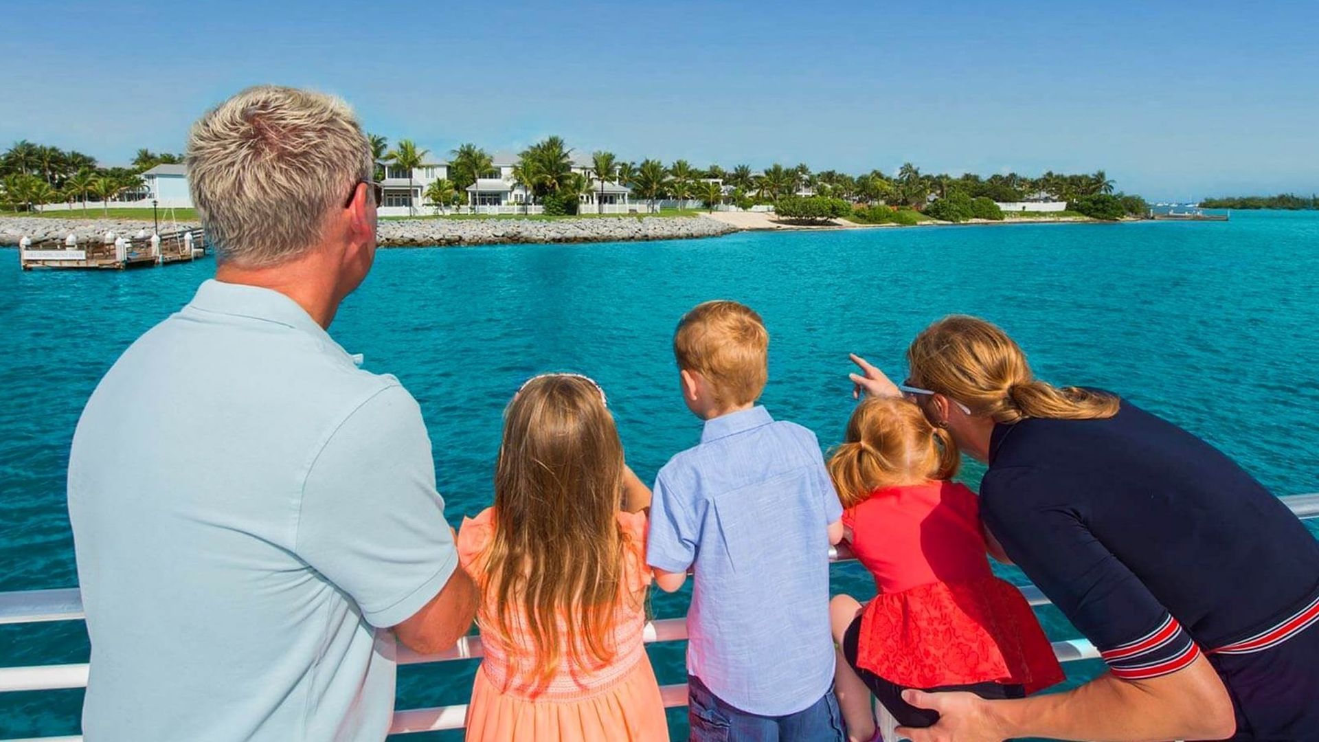 Family on a boat looking at turquoise water and a tropical island.