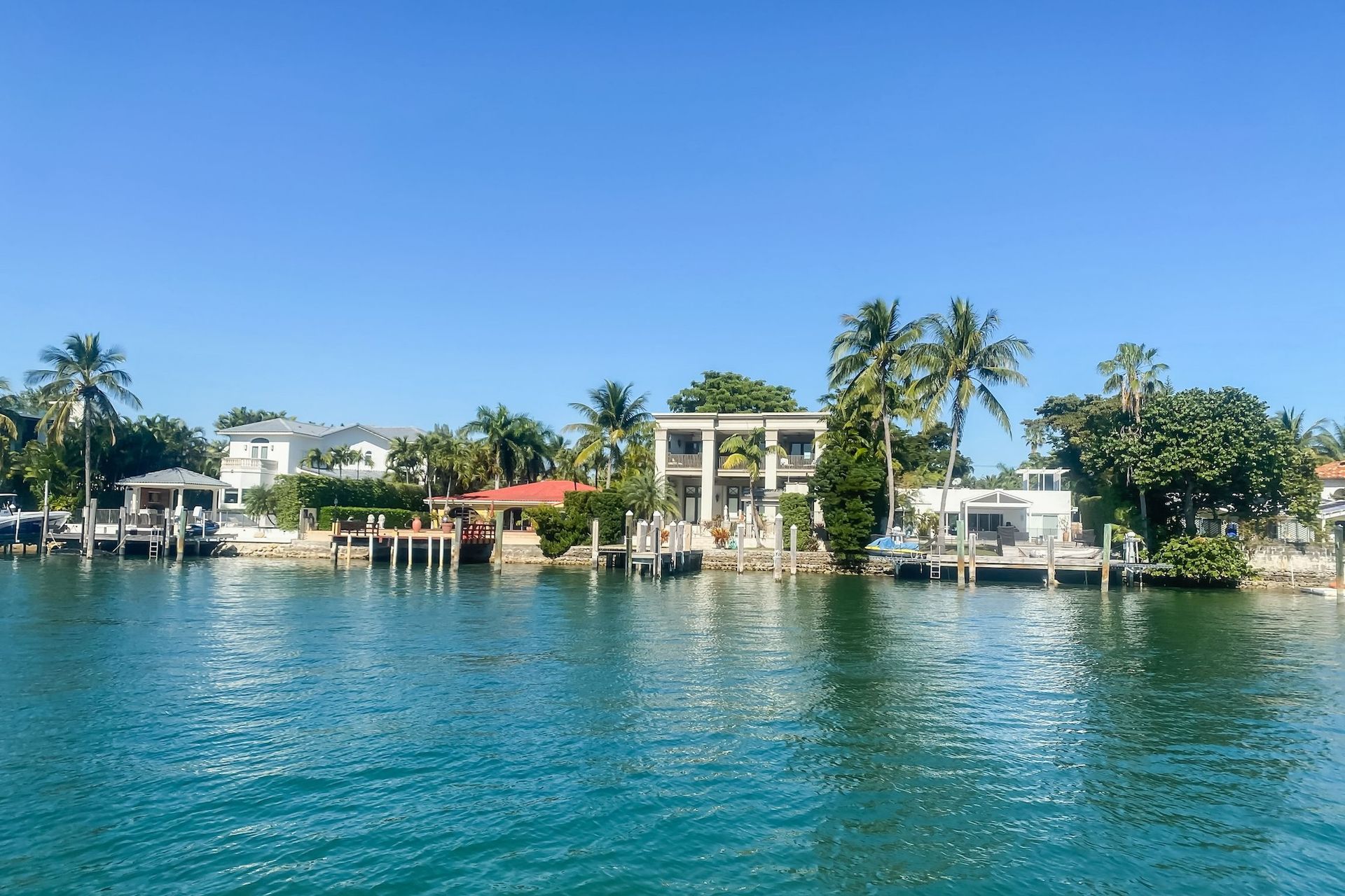 Waterfront homes with docks and palm trees under a clear blue sky.