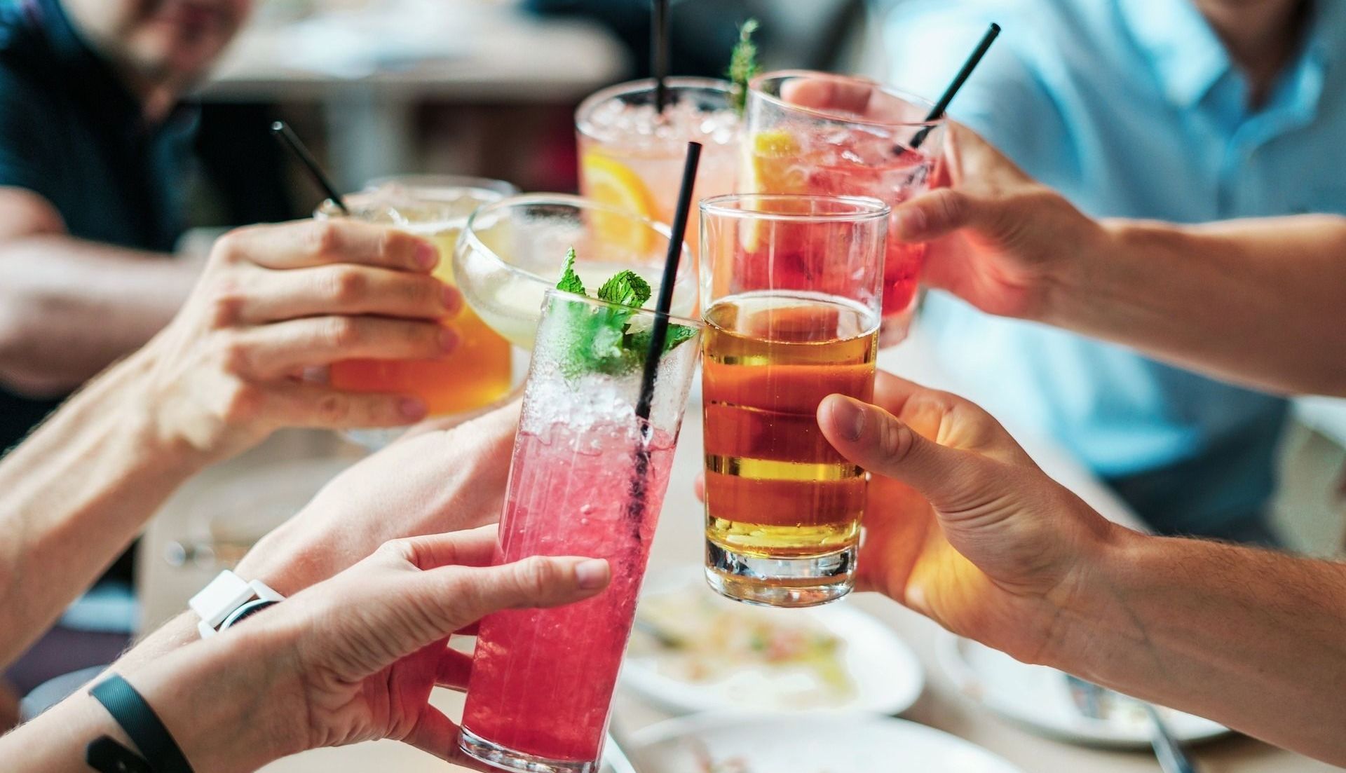People toasting with colorful cocktails at a restaurant.