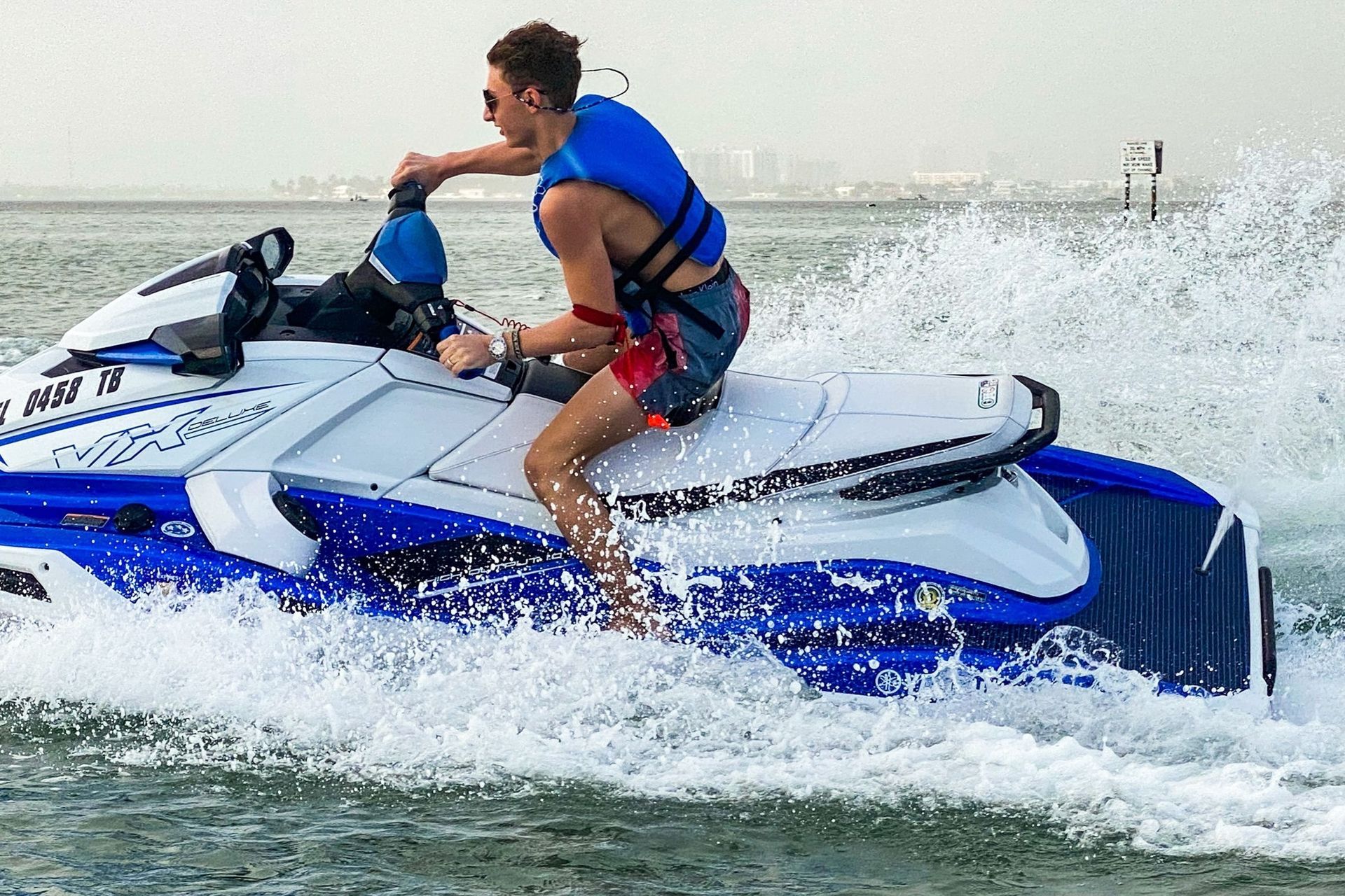 Man on a blue and white jet ski on water, creating a large splash.