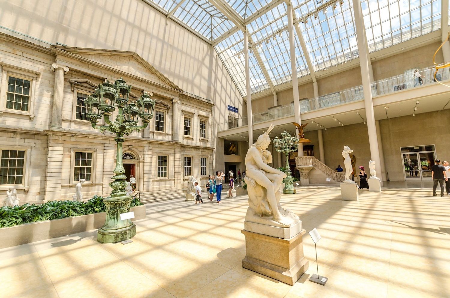 Inside the Metropolitan Museum of Art. Visitors in a large, bright hall with sculptures and classical architecture.