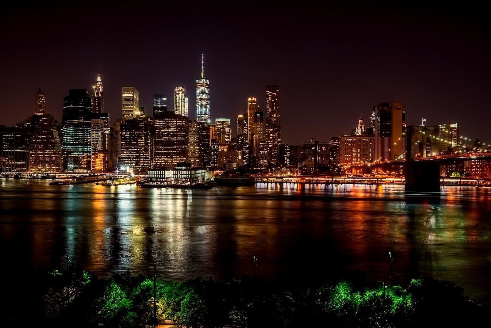 Night view of New York City skyline with glowing lights reflecting in the water below.