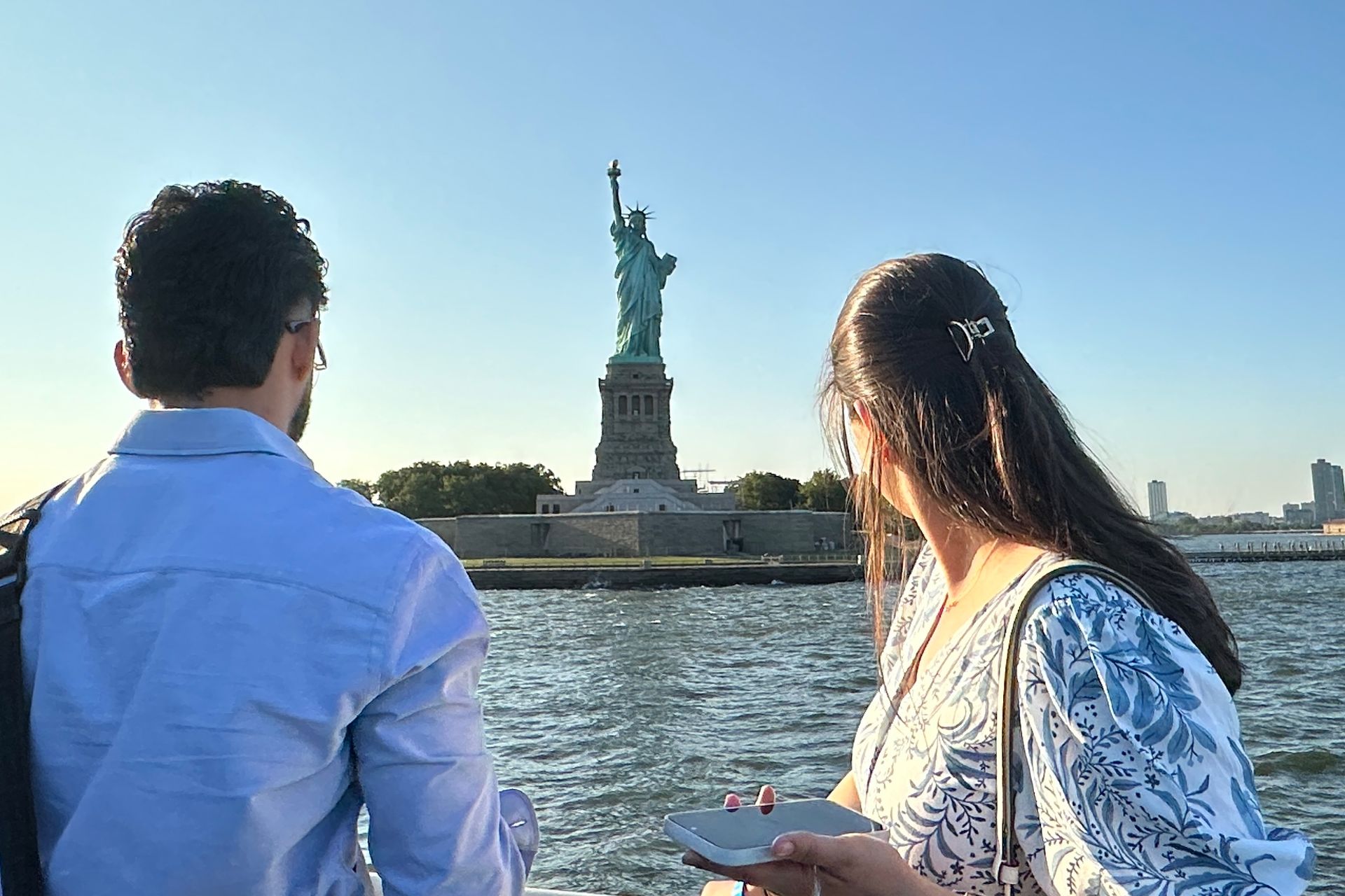Couple overlooking the Statue of Liberty on a sunny day.