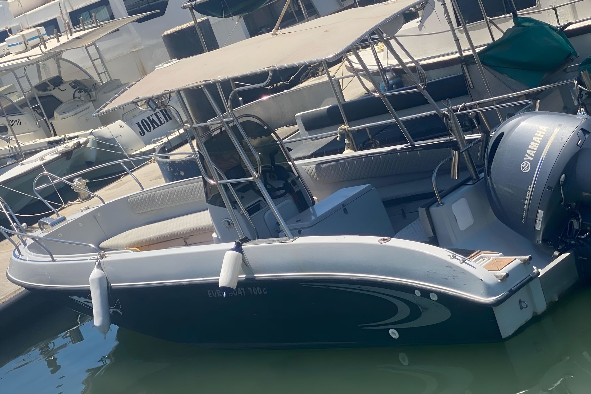 Boat with a Yamaha engine docked at a marina, canopy overhead.