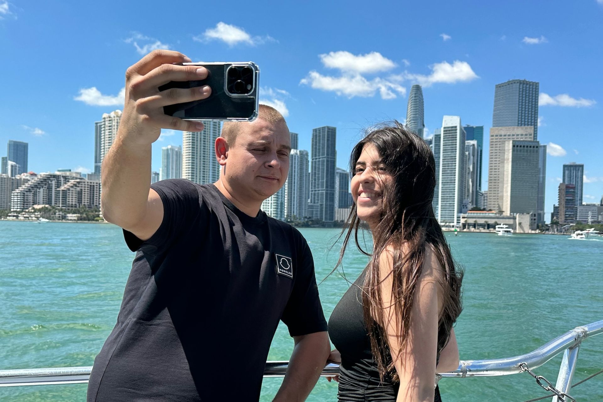 People relaxing on a boat with the Miami skyline behind them.