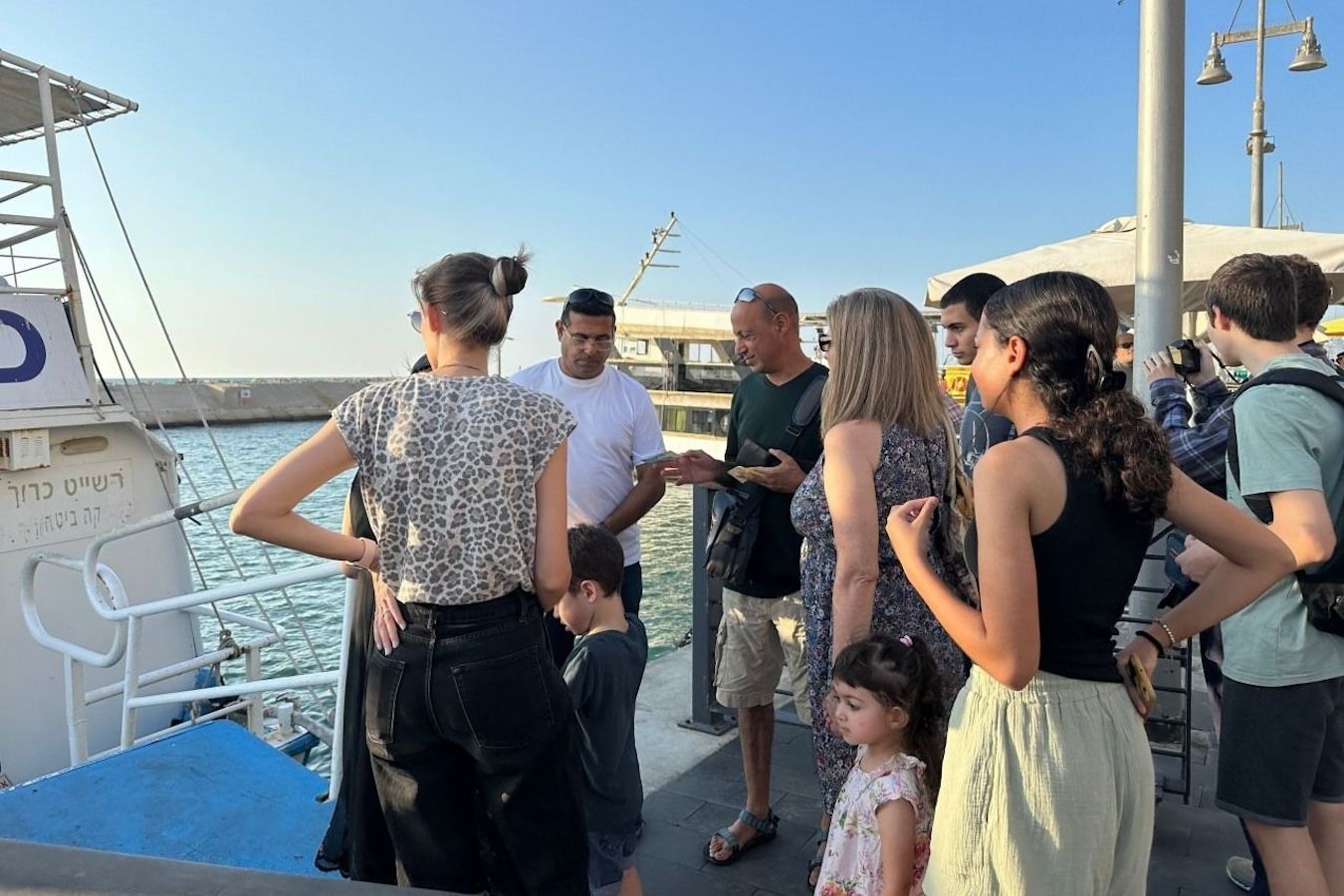 People boarding a boat in daylight; various ages and ethnicities.