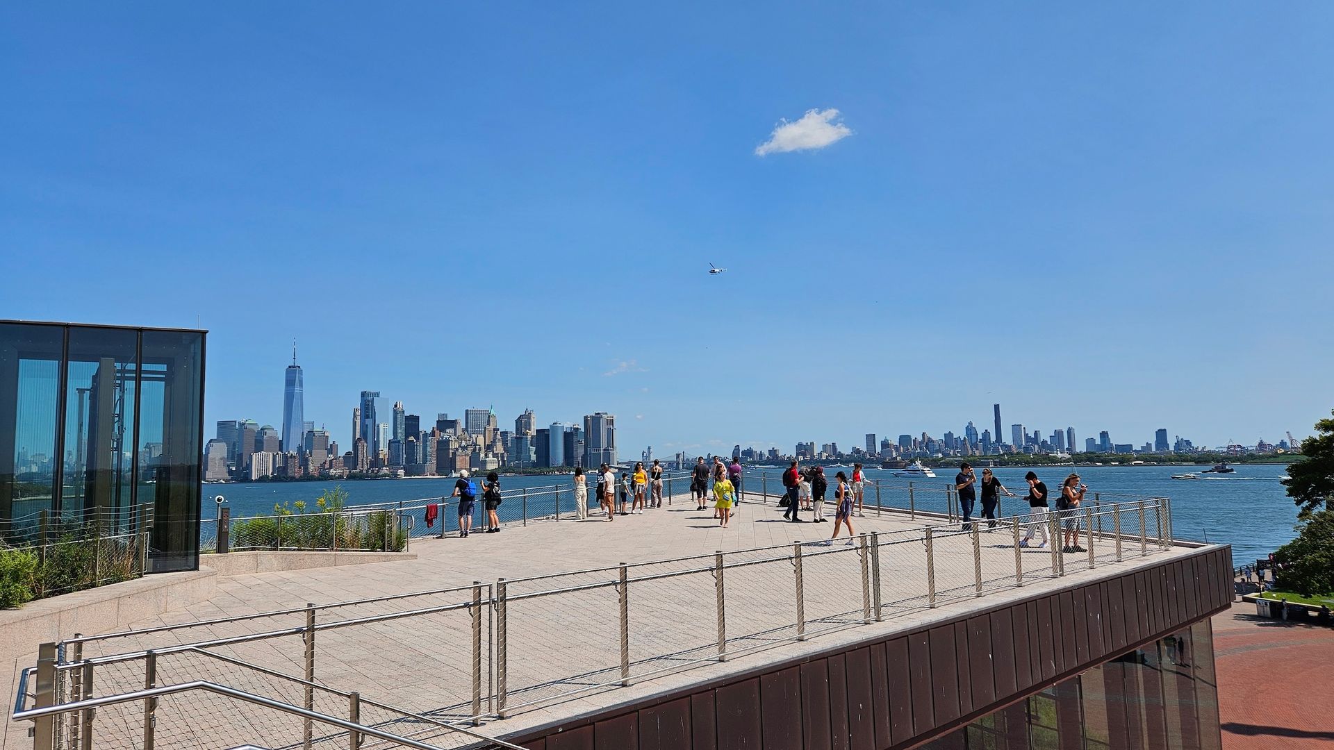 People on a pier overlooking a cityscape on a sunny day.