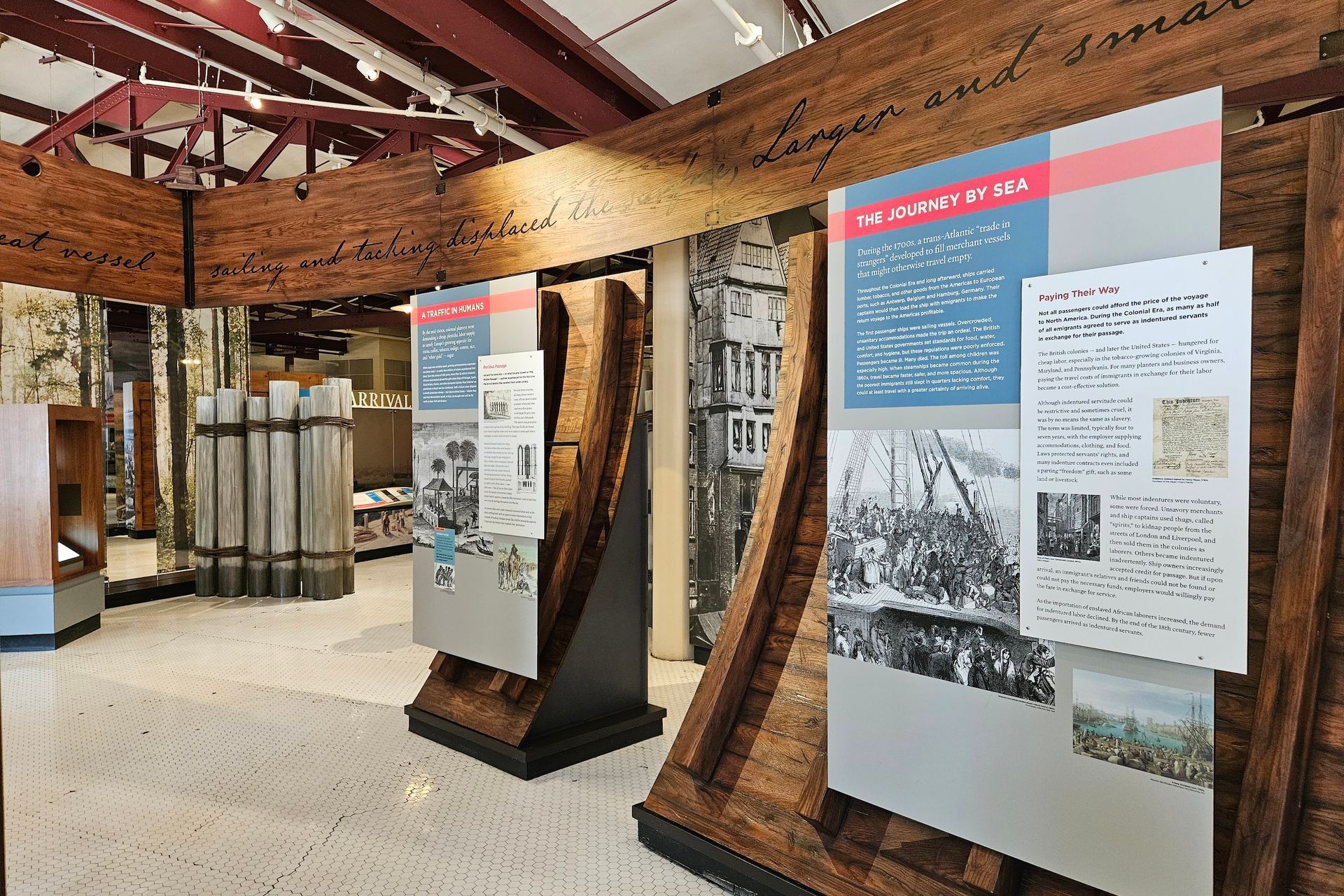 Museum exhibit: wooden structures with informational panels, displaying text and images.